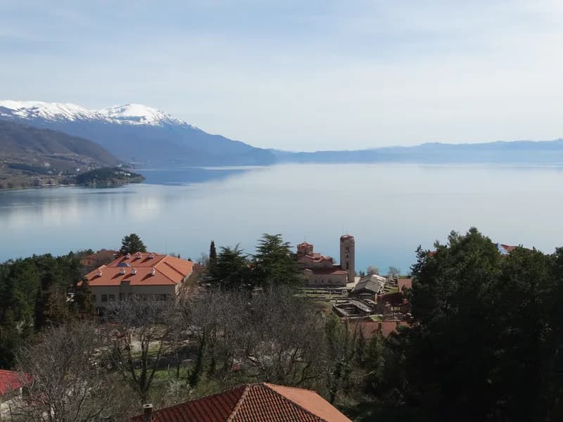 Lake Ohrid with snow-capped mountains beyond and the rooftops of Ohrid in the foreground.